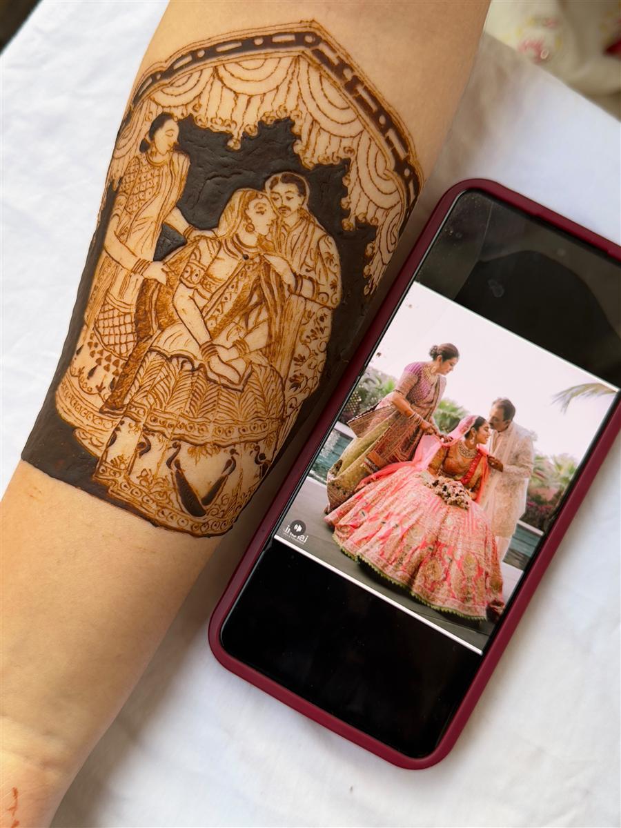 Wedding photo recreated in henna beside the reference phone